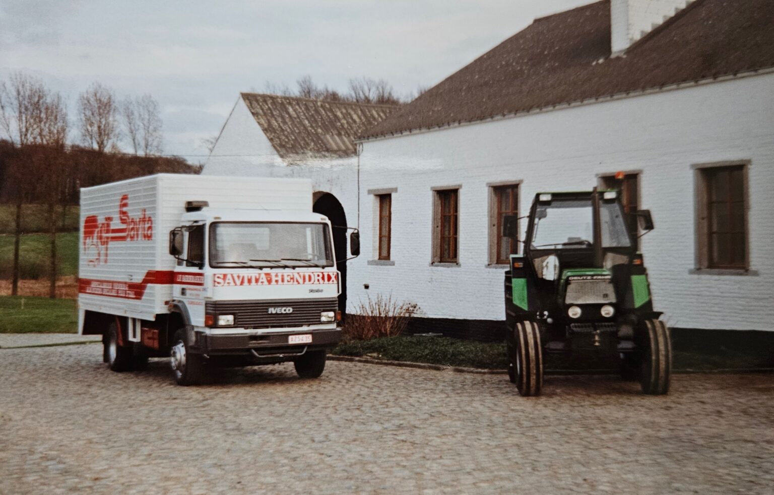 Vrachtwagen en tractor op het erf van een landbouwbedrijf, als illustratie van duurzaamheid, veeteelt en verantwoord ondernemen binnen een modern landbouwbedrijf.